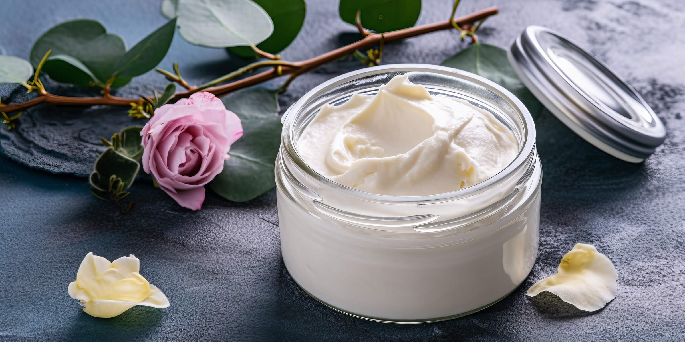 glass jar of body cream with pink rose behind